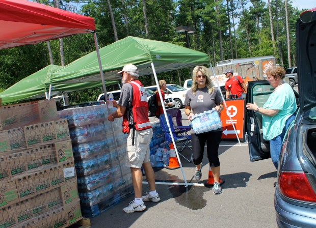 Red Cross volunteer Connie Barsness carried bottled water to the car of a local resident who was still without running water. The power is expected to return to the area in the next few days, but until then, local residents will continue to rely on alternative water sources.