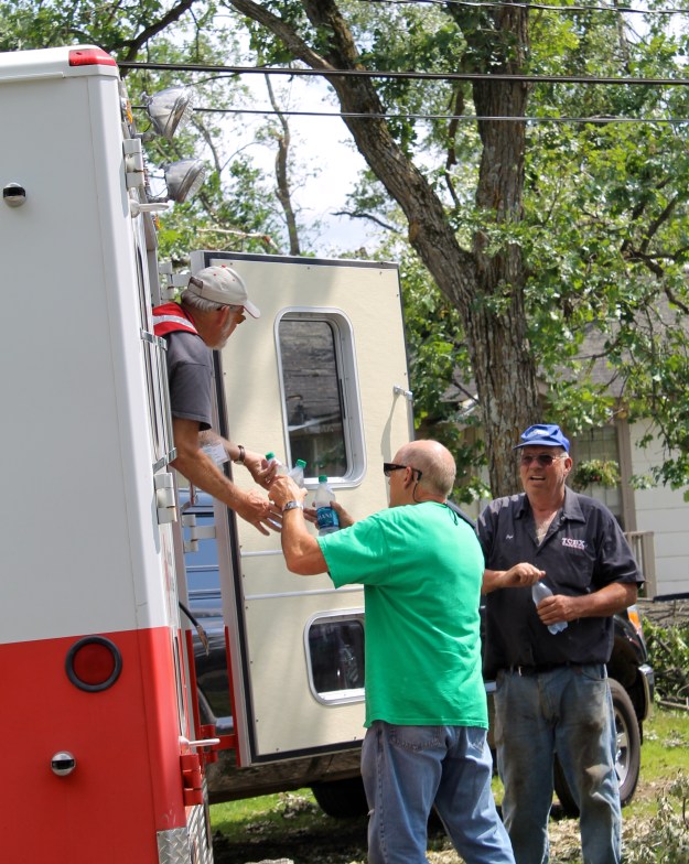 Red Cross volunteer Rick Campion distributes cold water to local residents Lloyd Baakkonen and Ronald Hines from the ERV. “We heard your horn and came running,” said Baakkonen, who despite having a tree through his roof had a huge smile on his face. “There’s nothing better than cold water.”